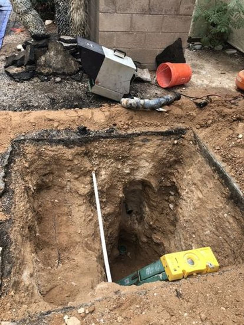 Excavation site showing deep hole with construction tools and materials nearby.